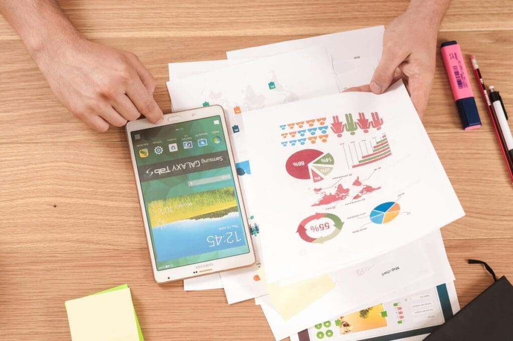 charts and graphs and icons on a pieces of paper, with a smartphone