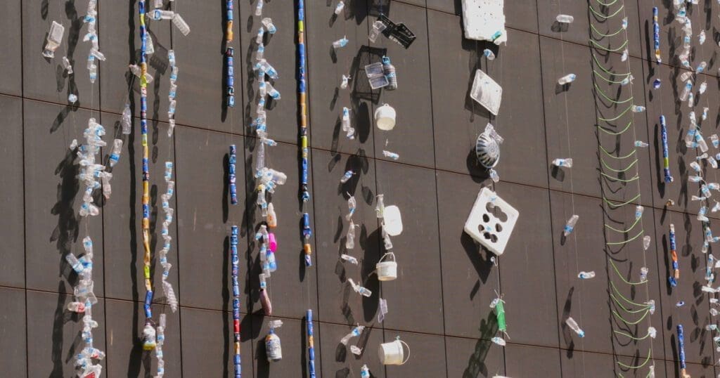 A large building with a plastic installation of trash hanging off the building