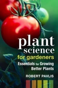 Ripe tomatoes on the vine with the book "Plant Science for Gardeners" in view.