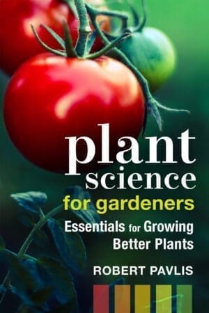 Ripe tomatoes on the vine with the book "Plant Science for Gardeners" in view.