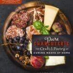 Pure Charcuterie board with meats, cheese, grapes, nuts, and peach on a dark surface.