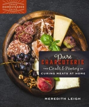 Pure Charcuterie board with meats, cheese, grapes, nuts, and peach on a dark surface.