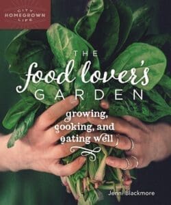Hands holding fresh spinach, presenting the book "The Food Lover's Garden.