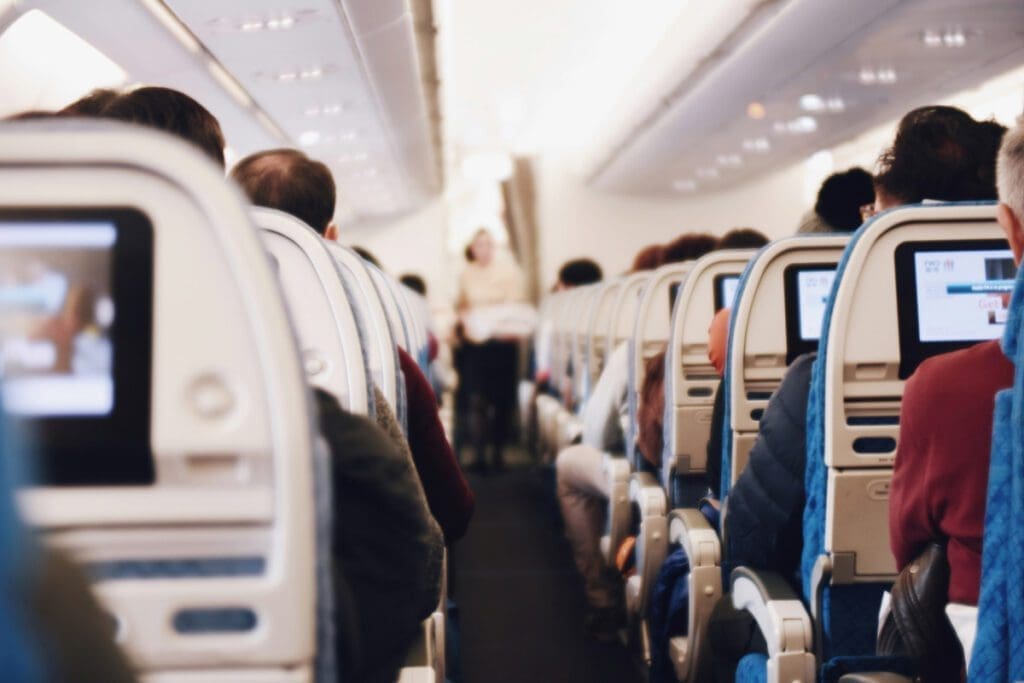 A view of passengers on an airplane from behind the back of the plane