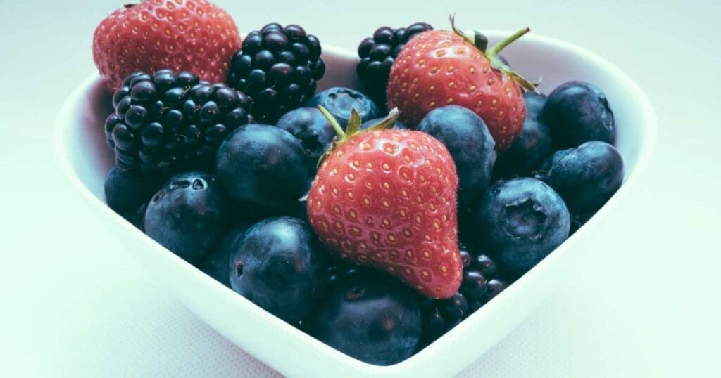 Strawberries, blueberries and raspberries in a squared bowl.