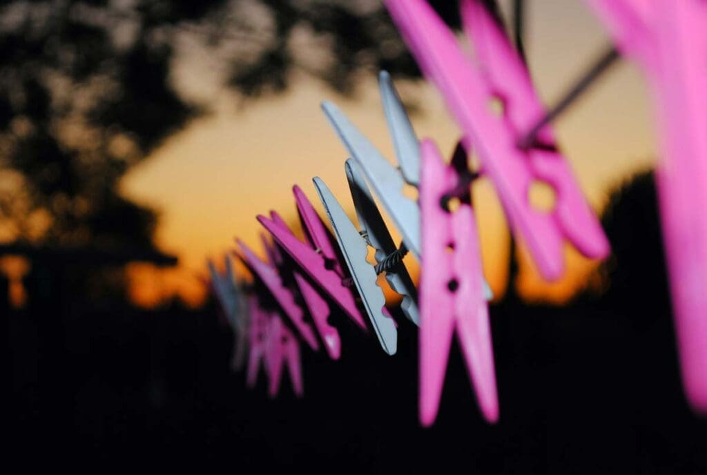 Light illuminates pink and blue clothes pins on a line at night.