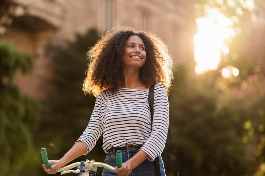 A smiling woman walking with a bike