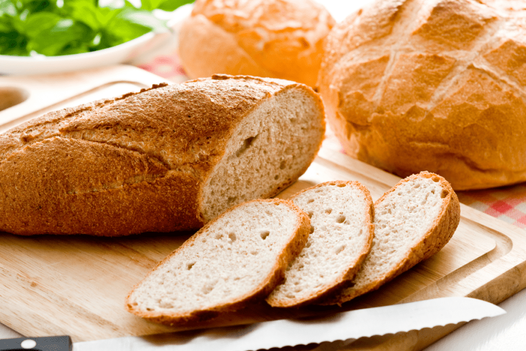 Fresh baked bread cut and cooling on a cutting board.
