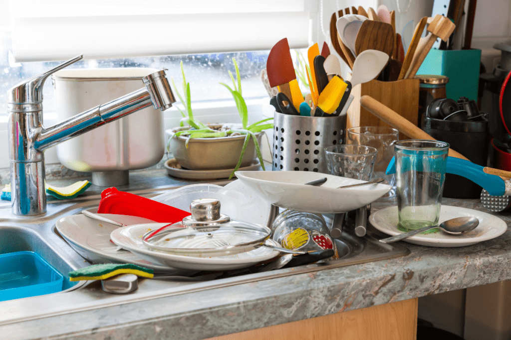 A sink filled with dirty dishes and cutlery.