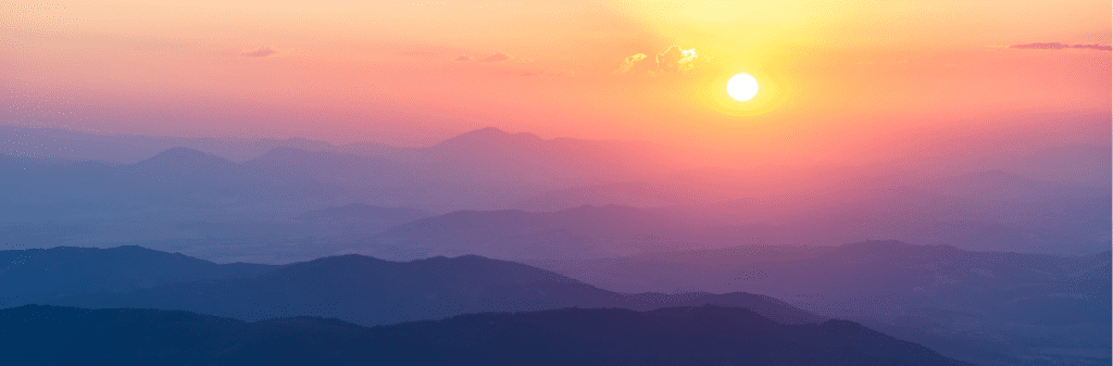 Sun setting over a mountain landscape.