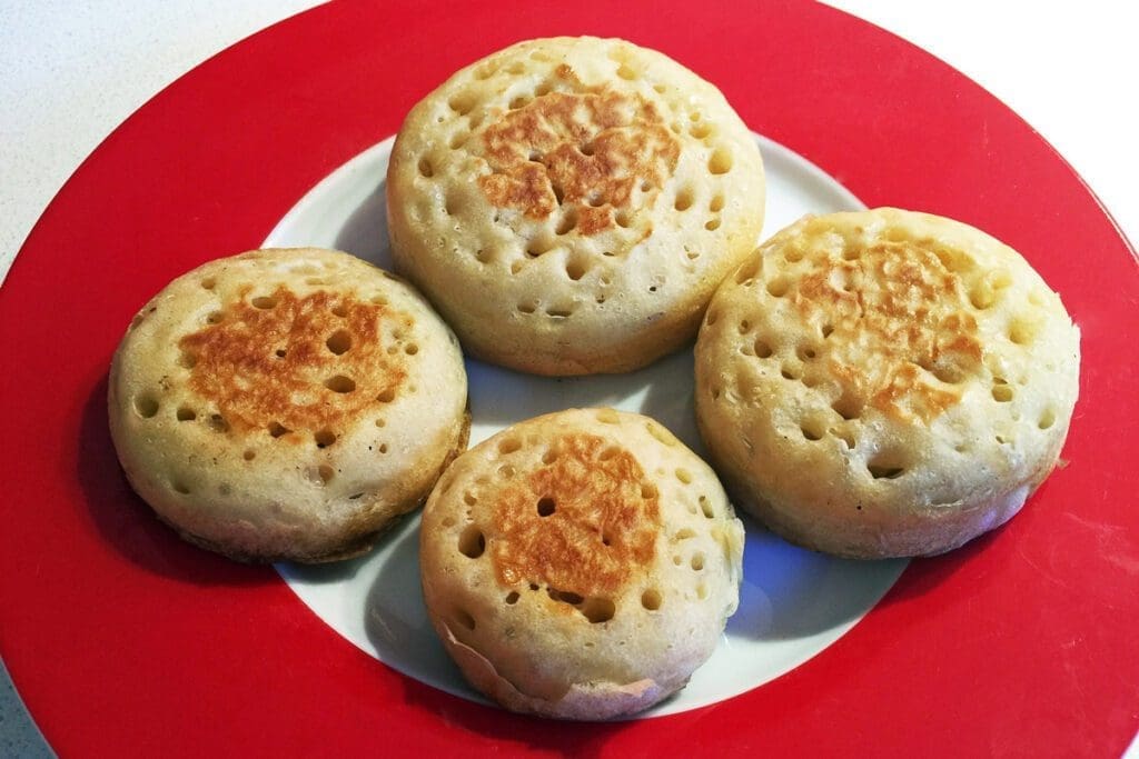 Four crumpets on a red plate