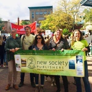 New Society Staff member at a rally, holding up a New Society banner