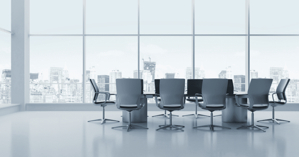 Empty office space in a high rise building with large windows featuring a large conference table.