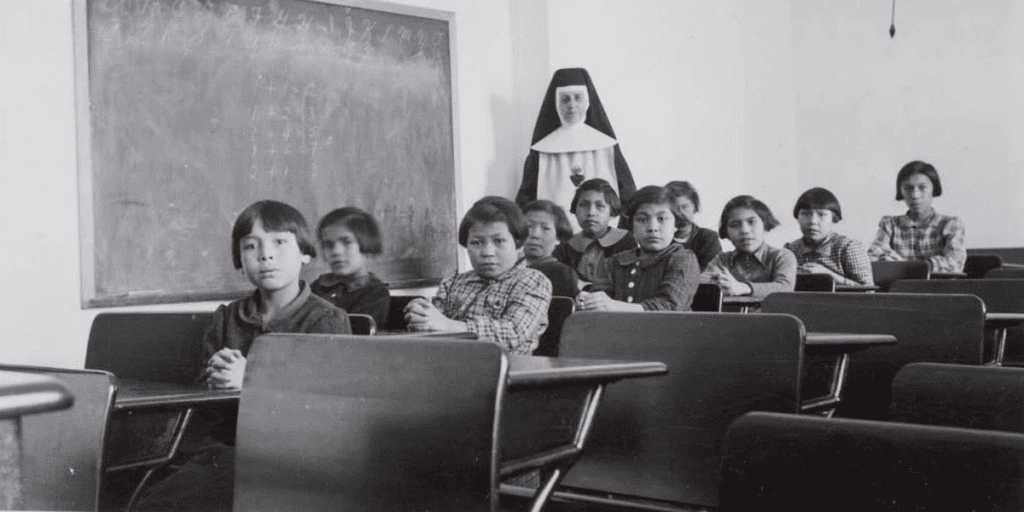 A class of children with a nun standing at the back near a chalkboard, symbolizing Bridging the Past and fostering a brighter future.
