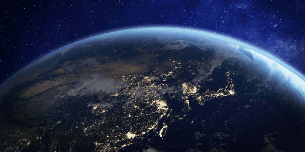 View of Earth from space at night, where the illuminated cities sparkle like jewels under a starry sky.