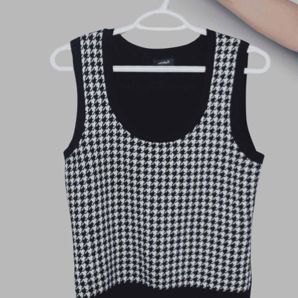 A houndstooth sweater vest on a hanger, offering a chic way to update your wardrobe sustainably.