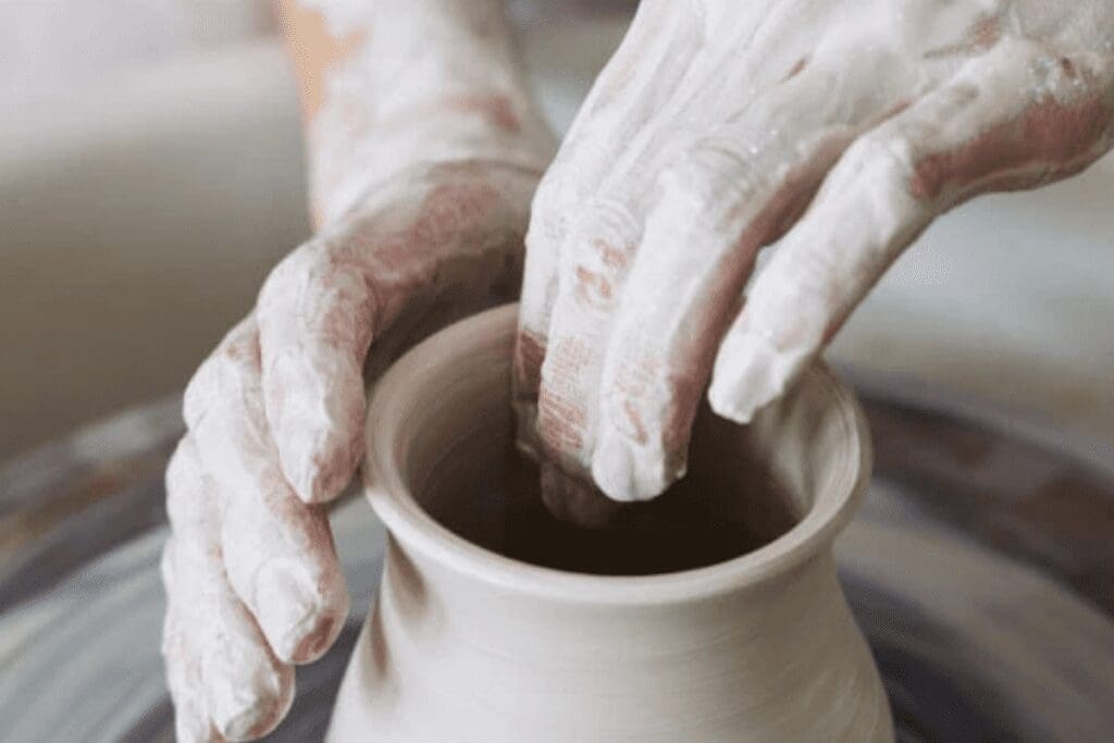 Hands shaping a clay pot on a pottery wheel, taking action to craft a better world.