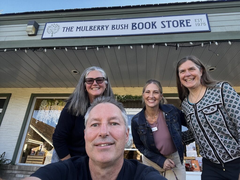 Four smiling people pose at Mulberry Bush Bookstore, a hub in the coastal community.