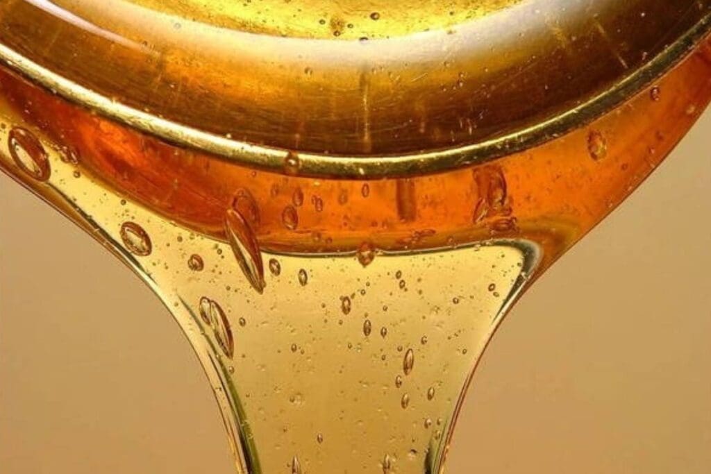 Close-up of golden honey being poured, capturing garden-to-table freshness in each bubble.
