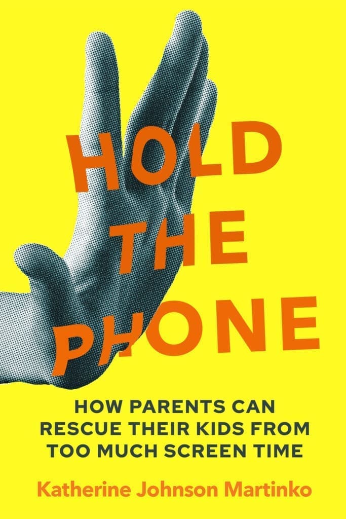 A hand holds the "Hold the Phone" product on a vibrant yellow background.