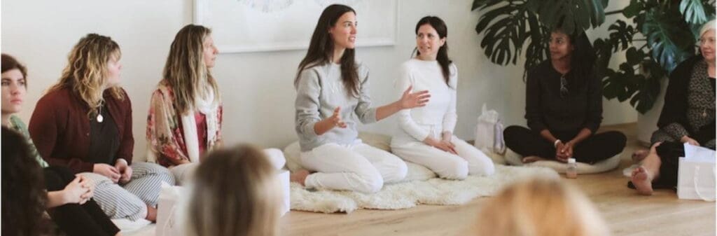 A group of women sit in a circle, as a workshop facilitator holds space for discussion.