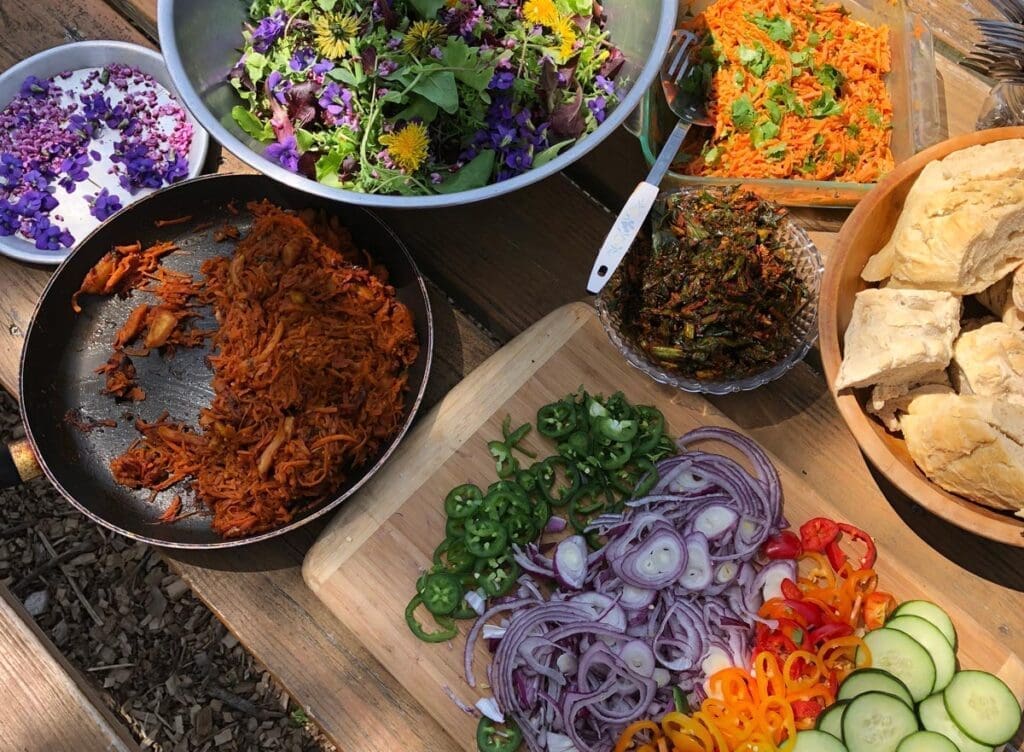 Colorful vegetables, herbs, and breads set outdoors for a fresh Yard to Table Eating experience.